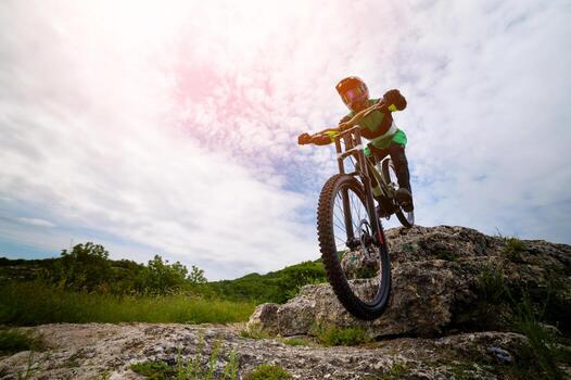 Cyclist riding a mountain bike down a cliff with beautiful countryside in the background. Extreme sport and enduro bike concept photo