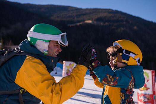 father preparing his little son for the first time on a snowboard photo