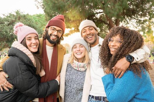 Group of friends looking at camera smiling outdoors in a park in winter. photo