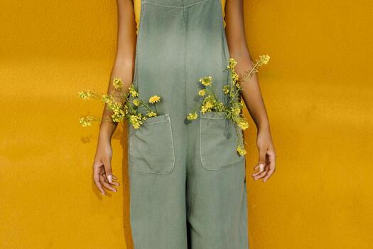 Midsection of woman wearing overalls with yellow flowers in pockets photo