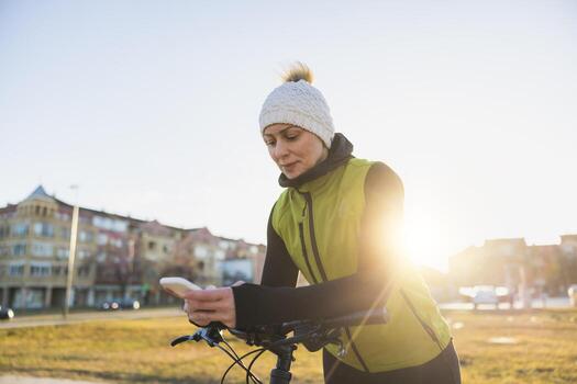 Woman Using Smartphone While Leaning on a Bicycle photo